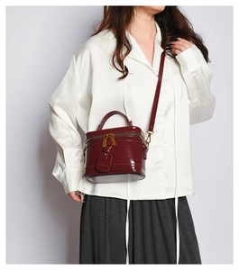Detail of burgundy box bag in glossy patent leather with vintage gold hardware