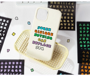 Gros plan de la coque iPhone crème avec typographie colorée et autocollants de bricolage