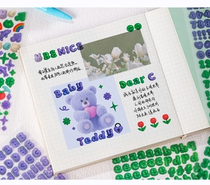 Détail d'autocollants alphabet 3D avec ours violet et tulipe sur carnet à carreaux