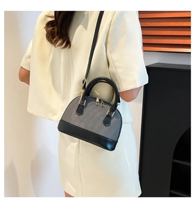 Detail of grey canvas and black leather shell bag with gold zippers and adjustable strap