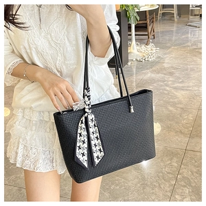 Close-up of a woven black tote bag featuring a stylish houndstooth scarf on the handle