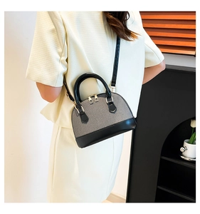 Detailed side view of a shell-shaped crossbody bag worn by a model in a modern interior