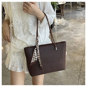 Detail of large brown patterned tote bag with stylish houndstooth scarf on the handle