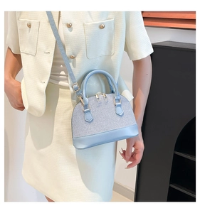 Detail of light blue shell handbag with woven fabric pattern and leather straps