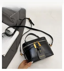 Detail view of black box bag showing top handle, dual zippers and adjustable strap