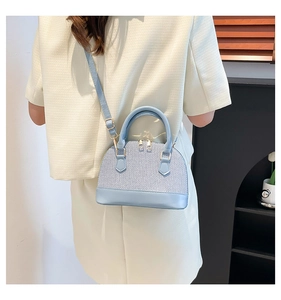 Blue and white striped shell crossbody bag shown on a model in a minimalist setting