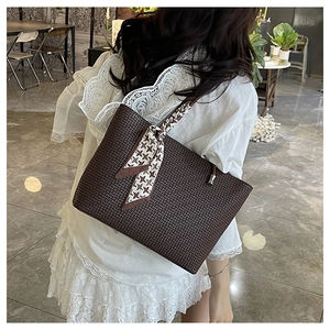 Detail of dark brown embossed tote bag with houndstooth scarf in a lifestyle setting