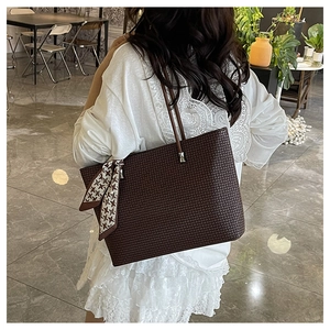 Detail of dark brown embossed tote bag with houndstooth scarf on a model in a cafe