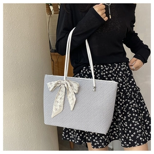 Detail view of woven tote bag with gray and white texture and decorative star print scarf