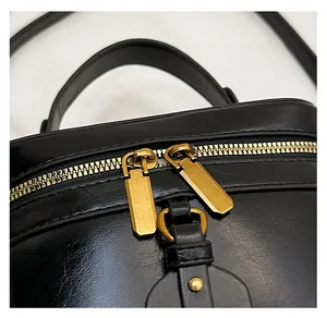 Detail of premium golden double zipper on black patent leather box bag top handle