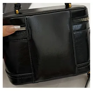 Close-up of black box bag showing textured synthetic leather and gold zipper details