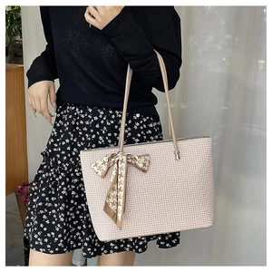 Detail of light pink tote bag featuring cross-pattern texture and silk scarf handle decor