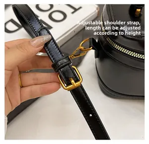 Detail of adjustable black leather shoulder strap with gold metal buckle and lobster clasp