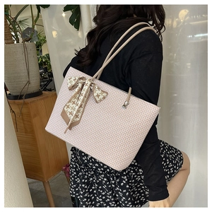 Detail of light beige tote bag with woven texture and houndstooth scarf on the handle