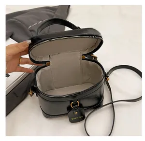 Detail view of black leather box bag featuring spacious interior with herringbone lining