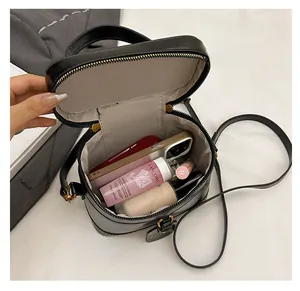 Interior view of black leather box bag showing capacity for phone and cosmetics
