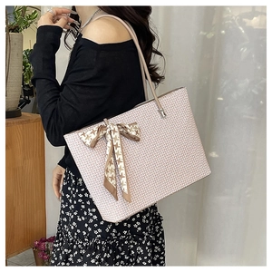 Detail of pink textured tote bag with houndstooth ribbon bow shown in a lifestyle setting