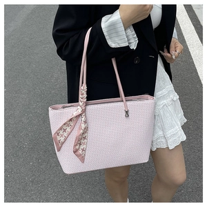 Detailed texture of pink woven tote bag with a decorative geometric silk scarf accent