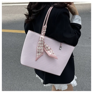 Close-up of pink woven tote bag with stylish houndstooth silk scarf on the handle