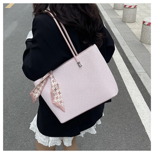 Pink embossed tote bag detail with decorative floral silk scarf on handle and geometric pattern