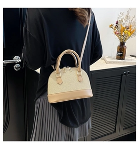 Detail of a beige shell crossbody bag with woven texture and gold metal zippers