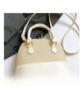 Detail of beige shell-shaped straw and faux leather bag with golden hardware