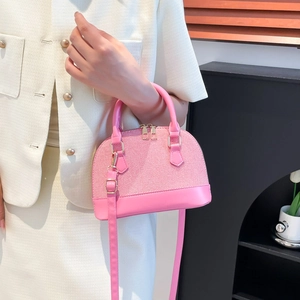 Pink shell-shaped handbag with textured fabric and leather handles in a front view