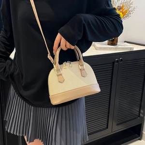 Classic beige woven shell handbag with gold hardware shown on a female model