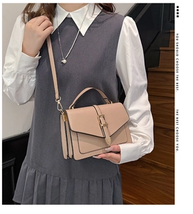 Beige faux leather crossbody bag with top handle shown on a model at a staircase