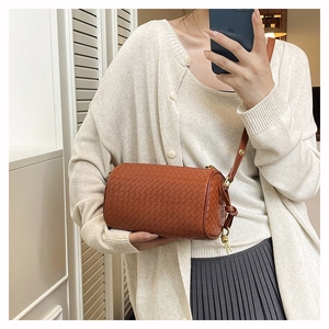 Detail of a brown woven leather cylindrical bag featuring classic Intrecciato craftsmanship