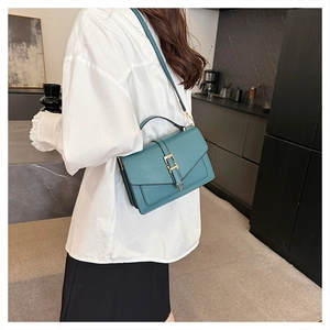 Modern dark green leather crossbody bag with gold buckle worn by model on shoulder