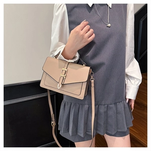 Detail view of a beige retro crossbody bag with a structured flap and golden hardware
