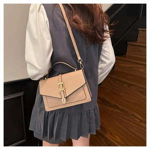 Side view of khaki leather crossbody square bag on model against urban background