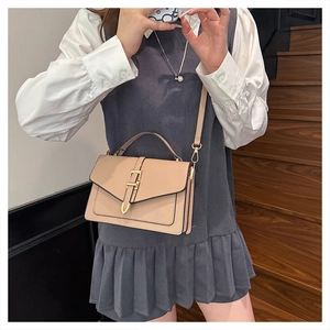 Beige faux leather crossbody bag with gold buckle on wooden stairs with a model