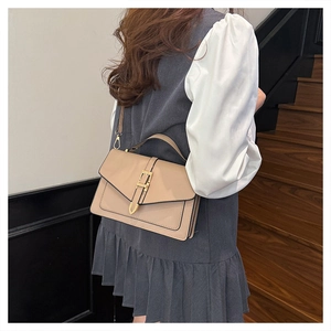Close-up of elegant beige leather handbag with gold metal clasp on a wooden staircase