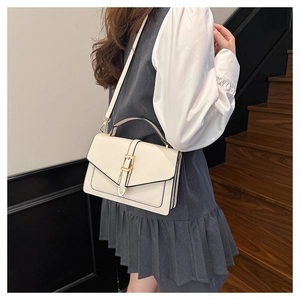 Side view of beige leather crossbody bag with gold buckle on a model in 80-100 characters