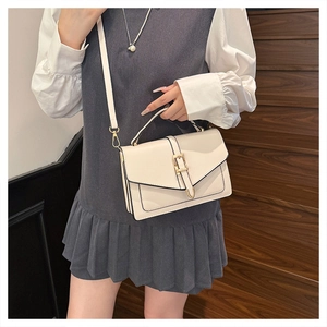 Close-up of cream leather crossbody bag with metal pin buckle shown on a model