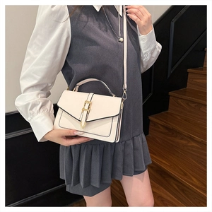 Detail of white leather handbag with gold metal buckle held by model on stairs