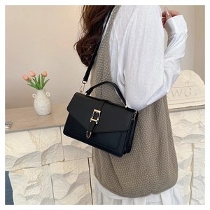 Detail of vintage black leather crossbody bag with gold buckle on a stylish model