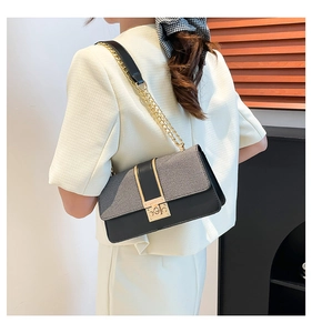 Close-up of elegant crossbody bag with gold chain strap and textured flap on model