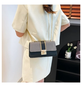 Detail of grey woven and black leather crossbody bag with golden chain and lock