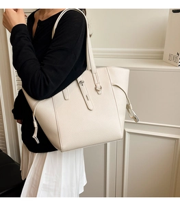 Detail of off-white lychee grain leather tote bag with metal twist lock and straps