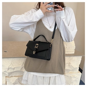 Detail of vintage black flap square bag with gold buckle on model in chic white shirt