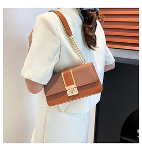 Detail of a brown leather and fabric patchwork crossbody bag with a gold clasp on a model