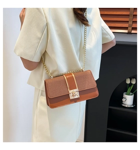 Detail of a brown patchwork crossbody bag with woven texture lid and gold chain strap