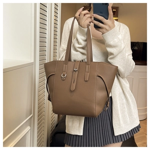 Detail of dark brown lychee leather tote bag with decorative straps and metal rings