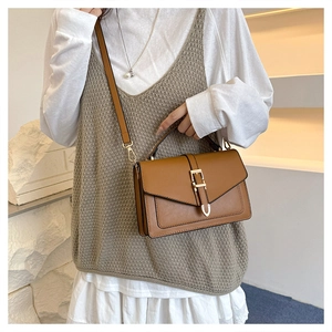 Brown leather crossbody bag detail with gold buckle clasp and smooth matte finish