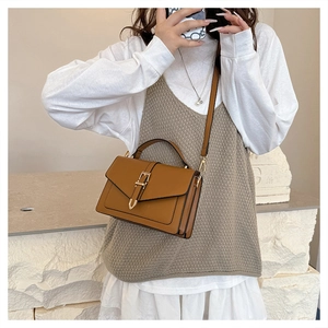 Brown leather crossbody bag with adjustable strap shown on a model in a minimalist setting