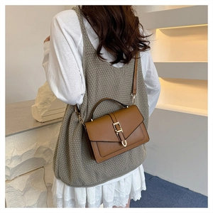 Detail of caramel faux leather bag featuring a gold U-shaped clasp and adjustable strap
