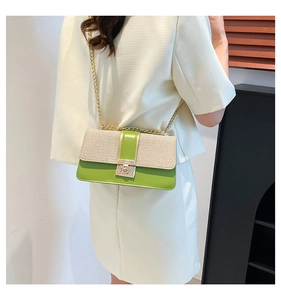 Detail of green and beige chain crossbody bag showing metal lock on a white suit model